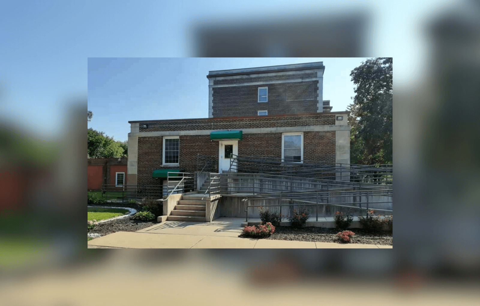 A brick building with a green door and steps leading up to it.